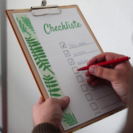 Mann hebt Klemmbrett und hakt Checkliste ab